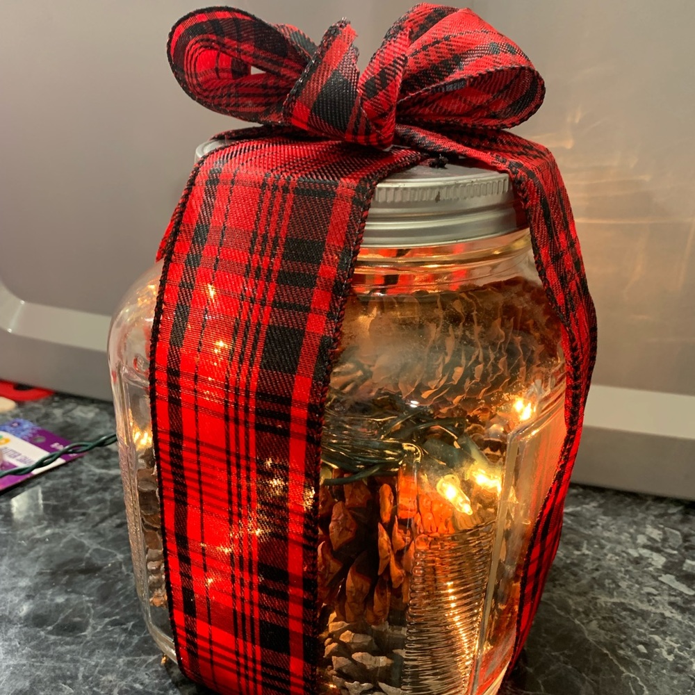 Lighted glass canister with pine cones